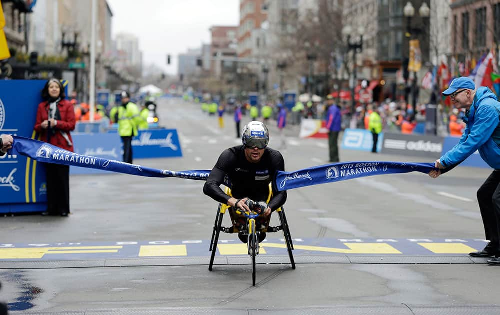 Marcel Hug, of Switzerland, breaks the tape at the finish line to win the wheelchair division of the Boston Marathon.