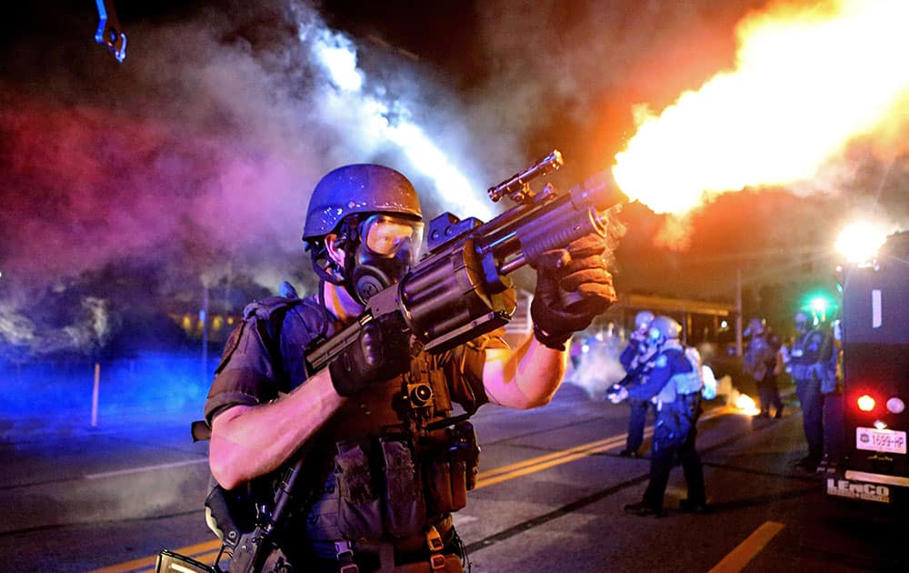 a member of the St. Louis County Police tactical team fires tear gas into a crowd of people in response to a series of gunshots fired at police during demonstrations in Ferguson.