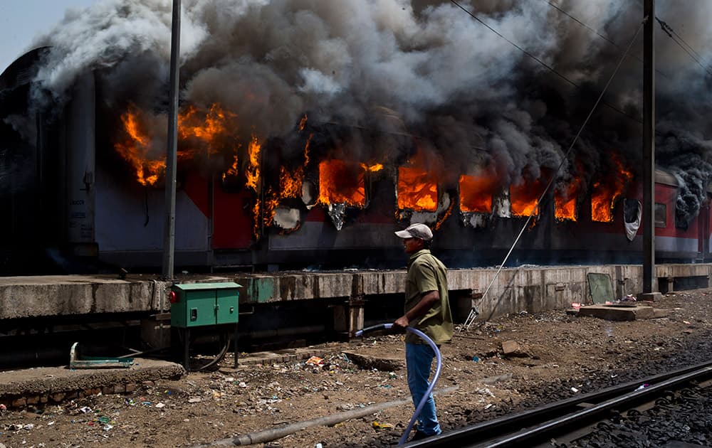 A worker waits for water as he prepares to contain a fire caught in the coaches of Sealdah Rajdhani train in New Delhi.