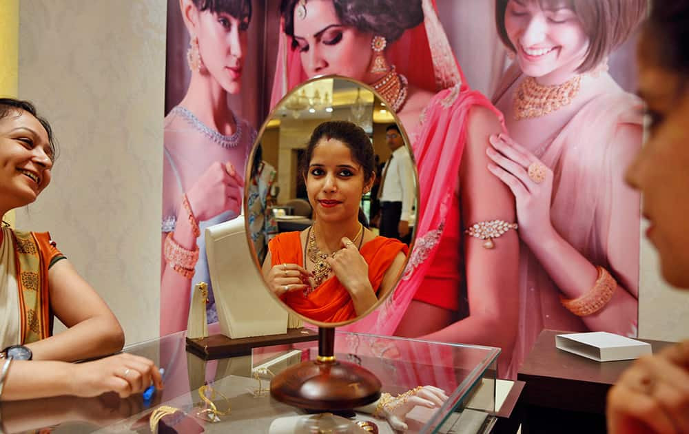 A customer, reflected on a mirror, tries a gold necklace at a jewelry shop in Allahabad. Tuesday marks the Hindu festival 'Akshay Tritiya' considered auspicious for buying gold among other things.