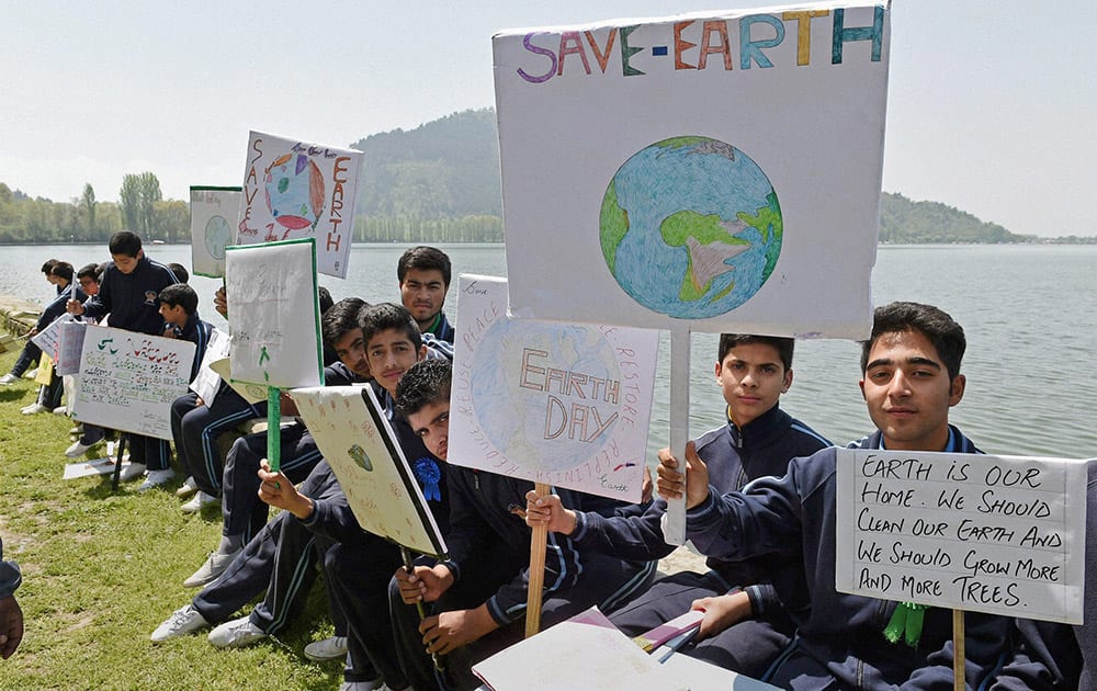 School children hold placards sitting on the banks of Dal Lake to mark World Earth Day.