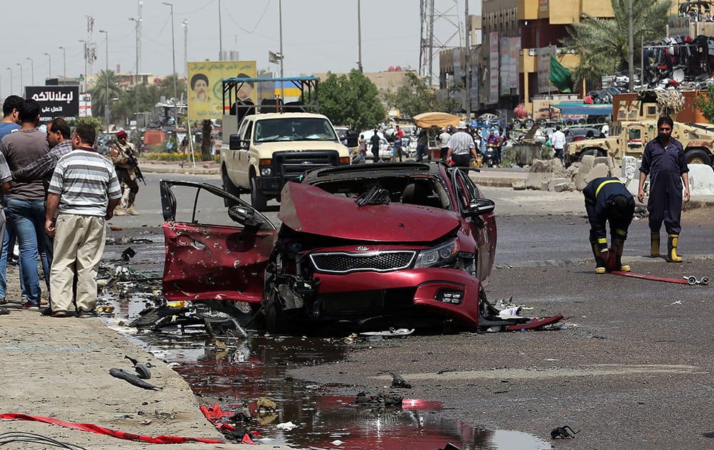 Civilians and security forces gather at the scene of a car bomb explosion in Talibiya in eastern Baghdad, Iraq.
