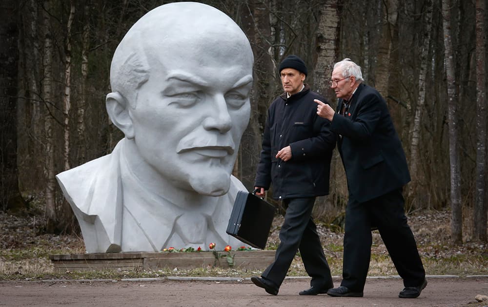 Russians walk past a statue of Soviet Union founder Vladimir Lenin during celebration of his 145th birthday at the Lenin Hut Museum at Razliv lake, outside St.Petersburg, Russia.