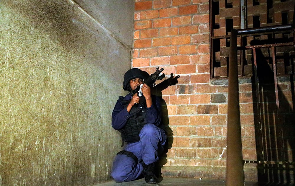 A police officer takes a position during their raid at a hostel in Alexandra township, Johannesburg, South Africa.