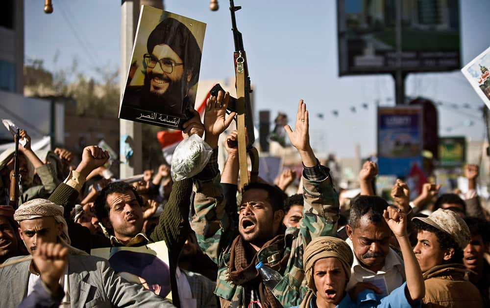 A Shiite rebel known as a Houthi, second left, holds a poster of Hezbollah leader Sheikh Hassan Nasrallah as he attends along with his comrades a protest to denounce the Saudi aggression in Sanaa, Yemen.