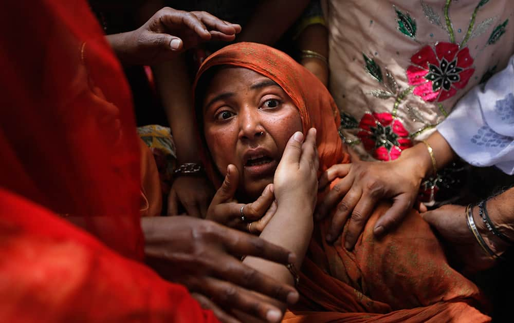 Local people console a shocked mother whose child was found under the debris of a residential building, in New Delhi.