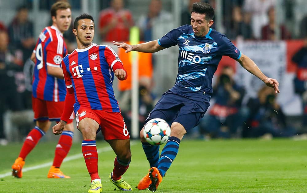 Bayern's Thiago, left, and Porto's Hector Herrera challenge for the ball during the soccer Champions League quarterfinal second leg match between Bayern Munich and FC Porto at the Allianz Arena in Munich, southern Germany.