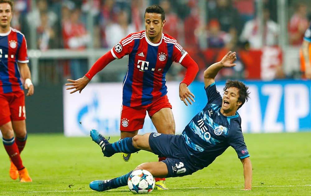 Bayern's Thiago, left, and Porto's Oliver Torres challenge for the ball during the soccer Champions League quarterfinal second leg match between Bayern Munich and FC Porto at the Allianz Arena in Munich, southern Germany.