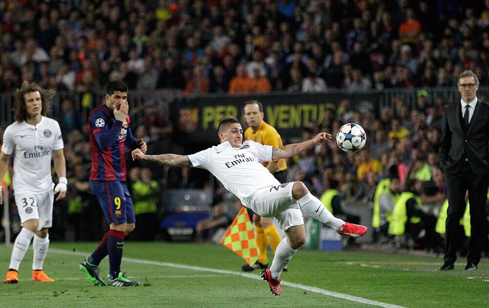 PSG's head coach Laurent Blanc, right, watches as PSG's Marco Verratti clears the ball during the Champions League quarterfinal second leg soccer match between FC Barcelona and Paris Saint Germain at the Camp Nou Stadium in Barcelona, Spain.