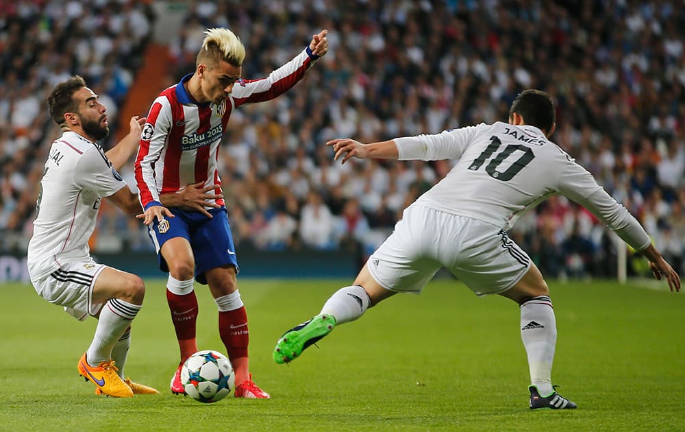 Real Madrid's Daniel Carvajal, left, uses his arm to restrain Atletico's Antoine Griezmann, center, as Atletico's Arda Turan, right, blocks during the second leg quarterfinal Champions League soccer match between Real Madrid and Atletico Madrid at Santiago Bernabeu stadium in Madrid, Spain.