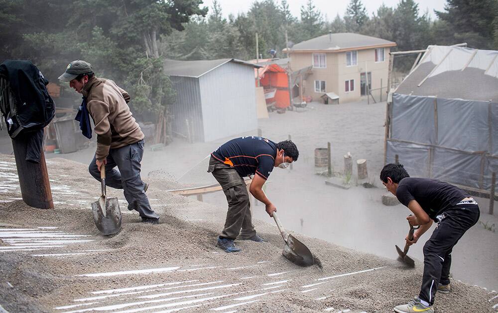 Men remove ash from a building's roof, left by the Calbuco volcano, in Ensenada, Chile.