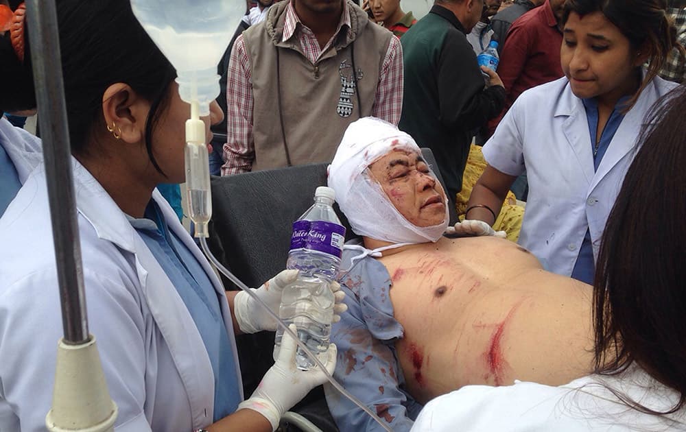 An Injured person receives treatment outside the Medicare Hospital in Kathmandu, Nepal. A strong magnitude-7.9 earthquake shook Nepal's capital and the densely populated Kathmandu Valley before noon Saturday, causing extensive damage with toppled walls and collapsed buildings, officials said.