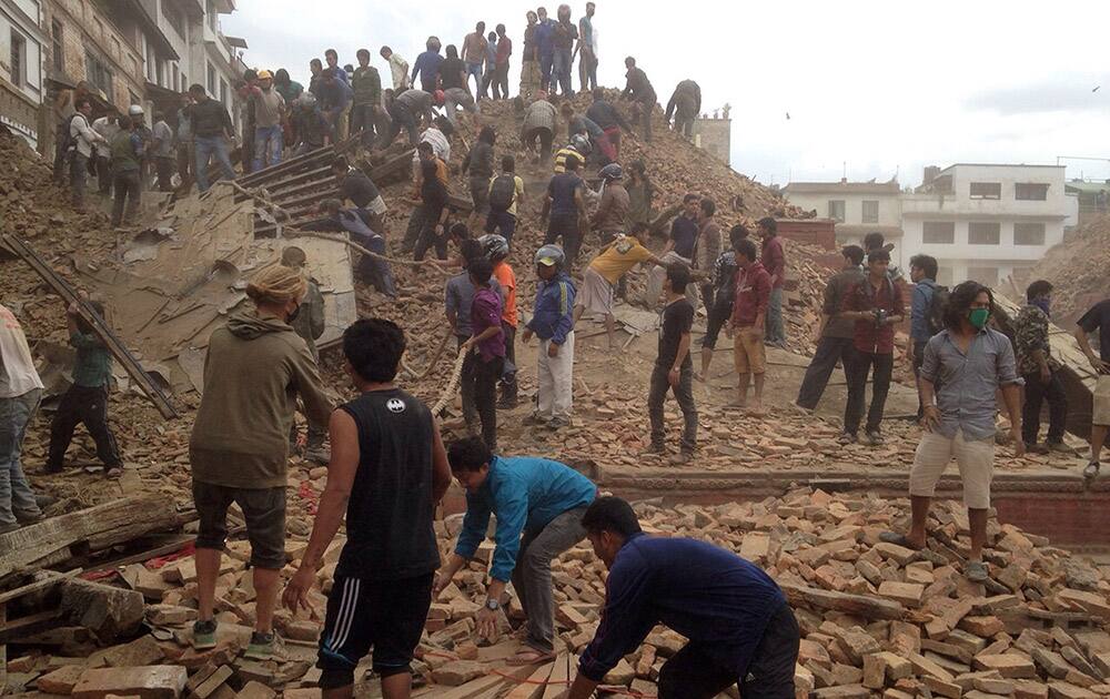 Volunteers help with rescue work at the site of a building that collapsed after an earthquake in Kathmandu, Nepal. A strong magnitude-7.9 earthquake shook Nepal's capital and the densely populated Kathmandu Valley before noon Saturday, causing extensive damage with toppled walls and collapsed buildings, officials said.