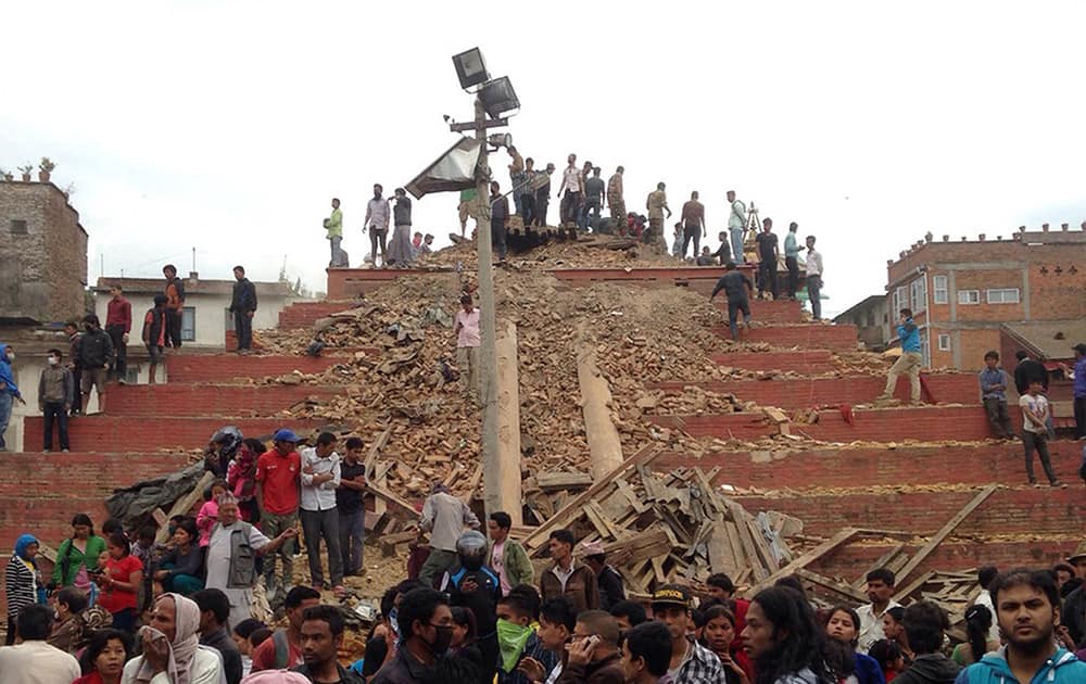 People stand around damage caused by an earthquake at Durbar Square in Kathmandu, Nepal. A strong magnitude-7.9 earthquake shook Nepal's capital and the densely populated Kathmandu Valley before noon Saturday, causing extensive damage with toppled walls and collapsed buildings, officials said. 