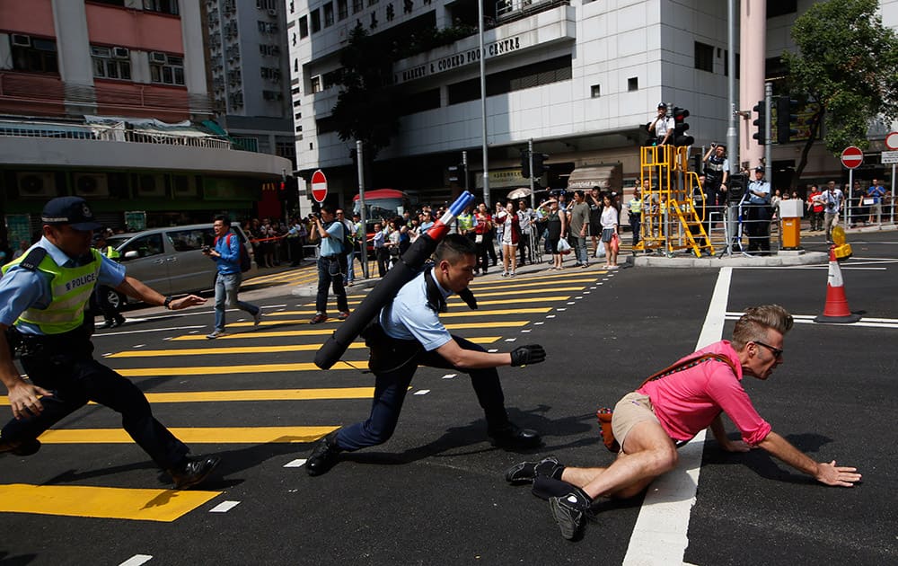 Police officers stop a pro-democracy protester, right, crossing the cordon line during a rally to promote the Hong Kong electoral reform in Hong Kong.