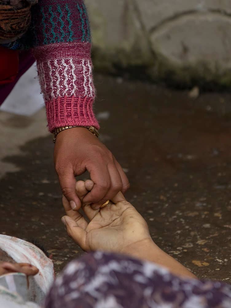 A Nepalese woman holds the hand of her relative killed in an earthquake at a hospital, in Kathmandu, Nepal, Sunday, April 26, 2015. 