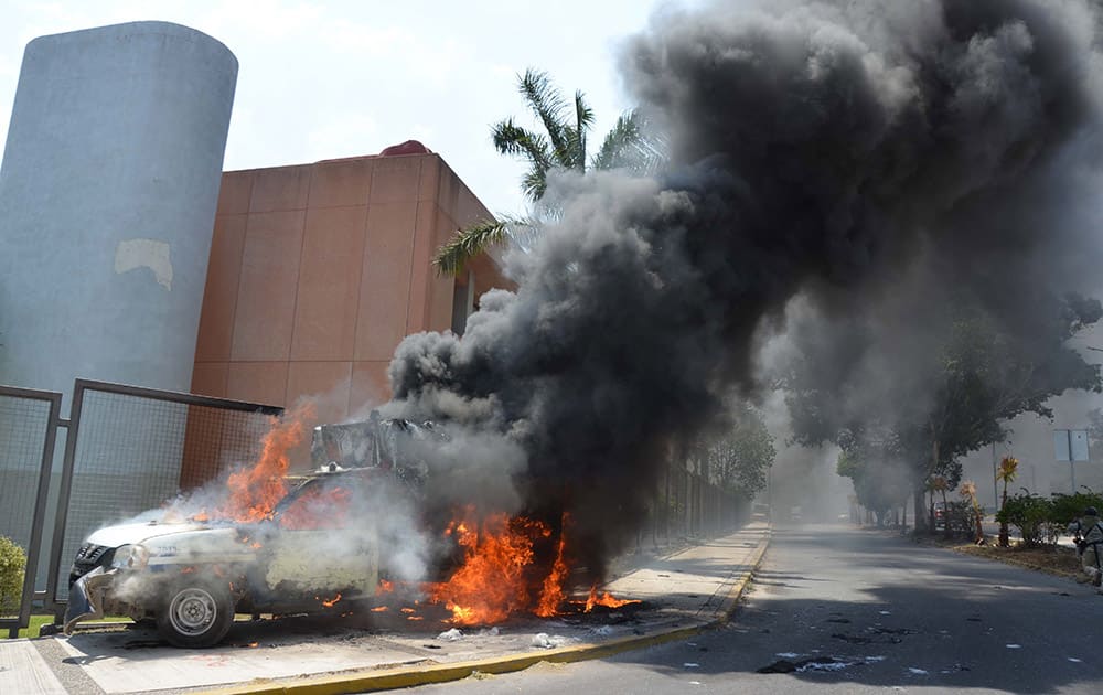 A truck that was torched by protesters burns near the main entrance of the state congress building in Chilpancingo, Mexico.