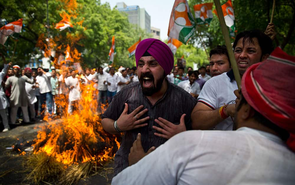 Farmers and Youth Congress party activists burn destroyed wheat as they protest against the government in New Delhi, India.