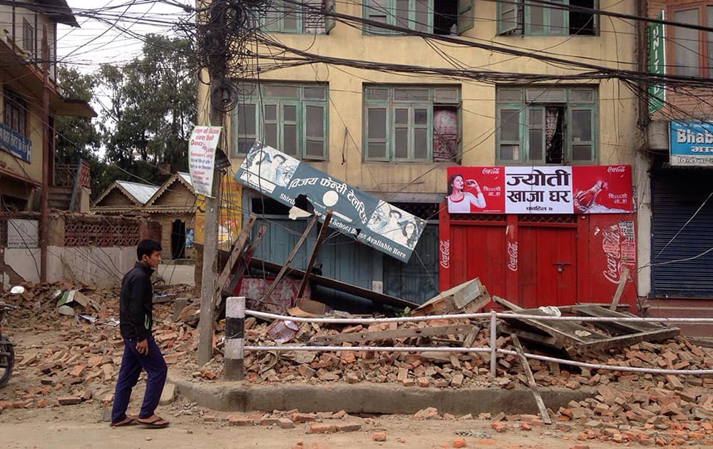 A man walks past damage caused by an earthquake in Kathmandu, Nepal, Saturday, April 25, 2015. A strong magnitude-7.9 earthquake shook Nepal’s capital and the densely populated Kathmandu Valley before noon Saturday, causing extensive damage with toppled walls and collapsed buildings, officials said.