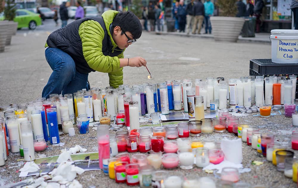 Kevin Lama, 12, of New York, keeps candles lit at a growing memorial after a deadly earthquake in Nepal.