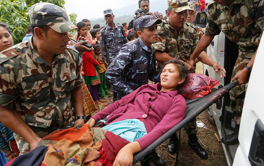 Sita Karka, suffering two broken legs from Saturday's massive earthquake, is assisted into an ambulance by Nepalese soldiers and police after arriving by helicopter from the heavily-damaged Ranachour village at a landing zone in the town of Gorkha, Nepal.
