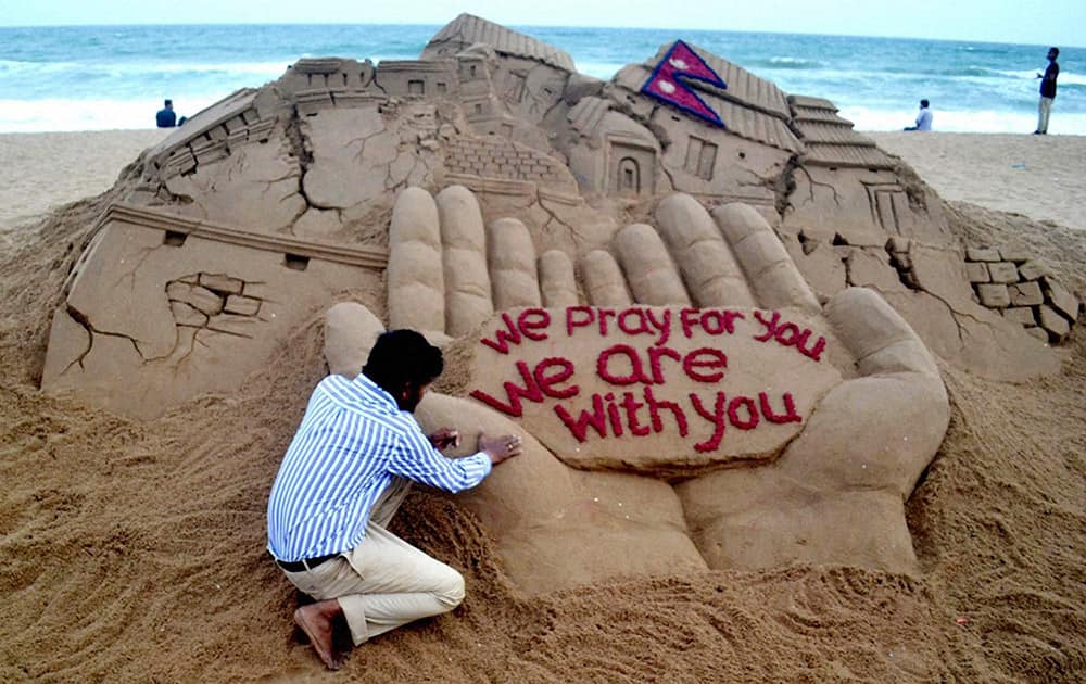 Sand artist Sudarsan Pattnaik creates a sand sculpture with a message We Pray for you - We are with You for Nepal earthquake victims, at Puri beach in Odisha.