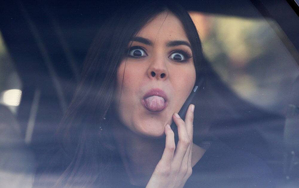 Miss Universe Paulina Vega, from Colombia, jokingly sticks her tongue out at photographers from a car after visiting patients at a military hospital in Bogota, Colombia.