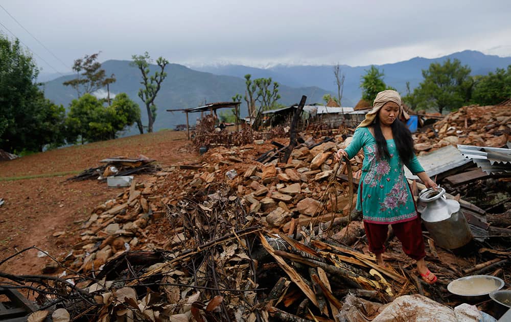 A woman recovers cooking pots from her collapsed home destroyed village of Paslang near the epicenter of Saturday's massive earthquake in the Gorkha District of Nepal.
