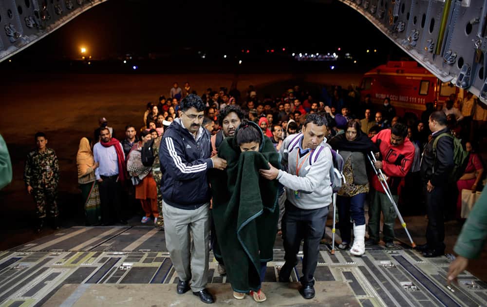 A survivor of Saturday's earthquake is helped to board a military plane evacuating injured and stranded Indians from Kathmandu to New Delhi during a midnight rescue mission by Indian Air Force, in Kathmandu, Nepal.