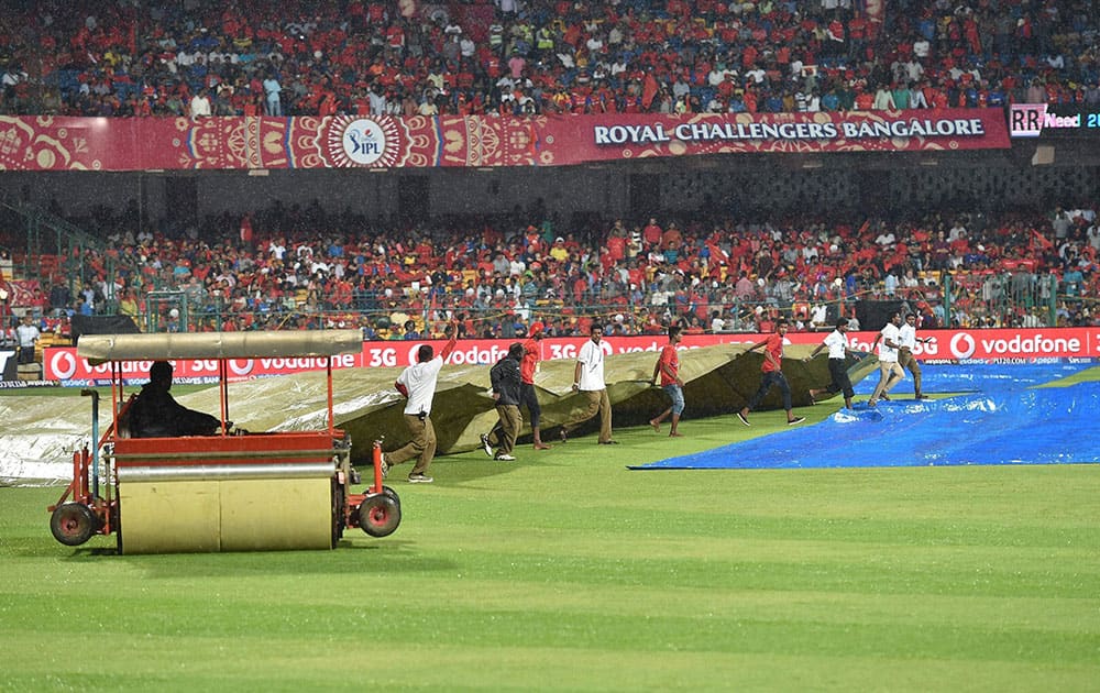 Ground men covering the pitch as it rains during the IPL match between Royal Challengers Bangalore and Rajasthan Royals in Bengaluru.