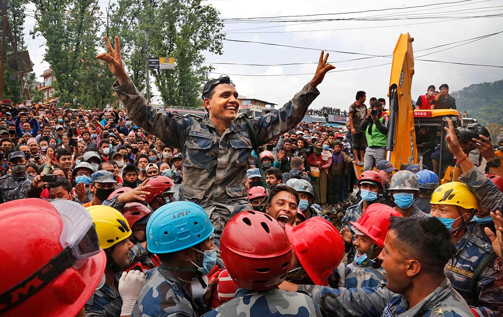 Nepalese policemen lift their commander and celebrate after they along with U.S. rescuers pulled out Pemba Tamang, a teenage boy from a building that collapsed five days ago in Kathmandu, Nepal.