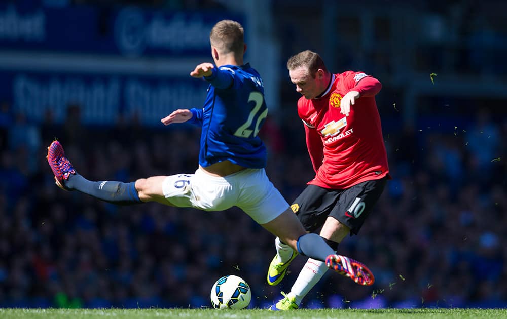 Manchester United's Wayne Rooney takes a shot as Everton's John Stones jumps in to block during the English Premier League soccer match between Everton and Manchester United at Goodison Park Stadium, Liverpool, England.