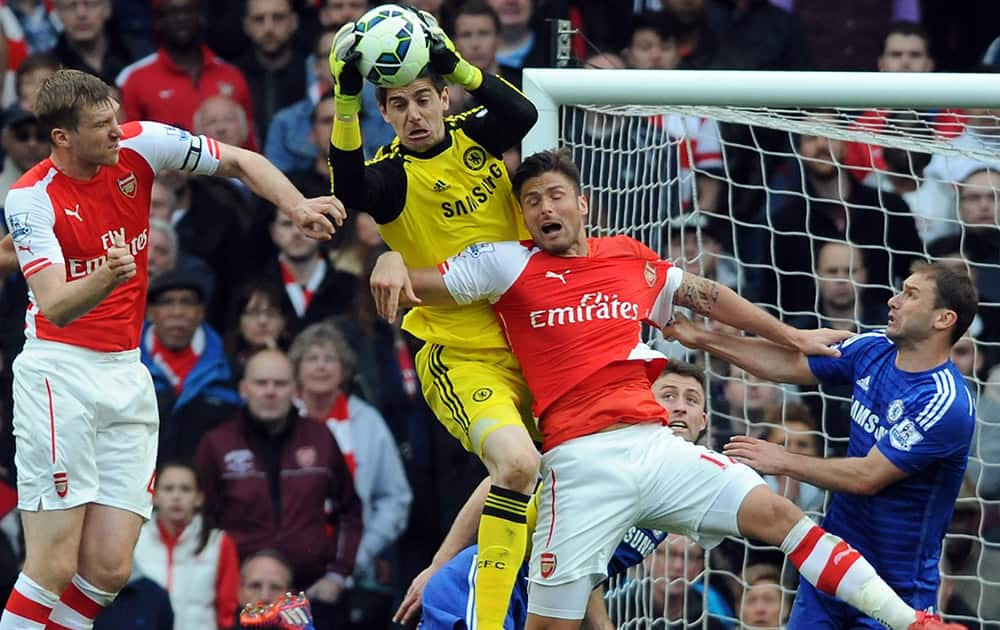 Chelsea goalkeeper Thibaut Courtois, centre, saves from Arsenal's Olivier Giroud, 2nd right, during the English Premier League soccer match between Arsenal and Chelsea at the Emirates Stadium, London, England.