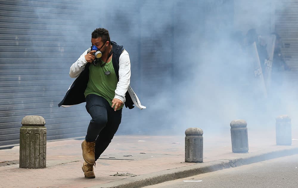 A protester runs from tear gas fire by police during a May Day march in Bogota, Colombia.