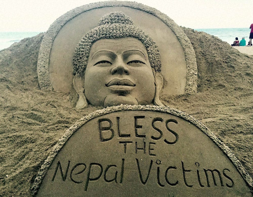 Sand artist Sudarsan Pattnaik creates a sand sculpture of Lord Budha with a message Bless the Nepal victims at Puri beach in Odisha.