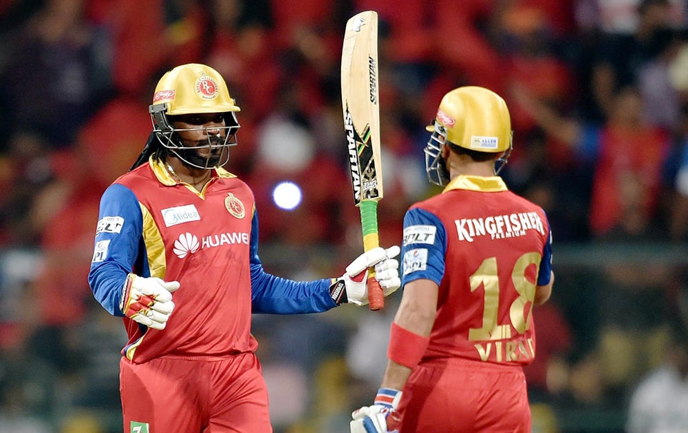 Royal Challengers Bangalore Chris Gayle raises his bat after competing his 50 runs during IPL 8 match against Kings XI Punjab in Bengaluru.