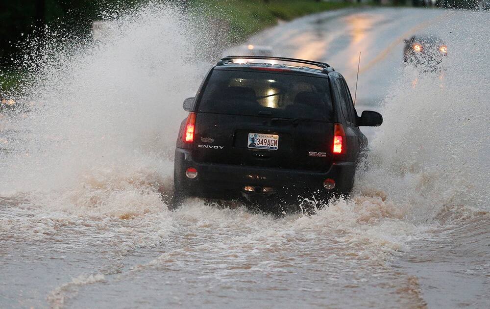 A vehicle makes its way through deep water following heavy rain in Moore, Okla.