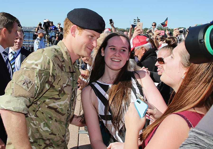 Britain's Prince Harry, poses for photos with a young girl in the crowd after arriving at the Opera House in Sydney, Australia. Prince Harry, or Captain Harry Wales, as he is known in the British Army, spent four weeks embedded with a number of Australian army units and regiments in Darwin, Perth and Sydney.