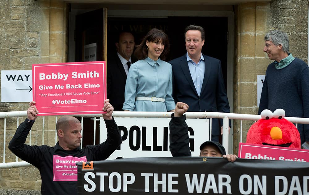 Britain's Prime Minister and Conservative Party leader David Cameron and his wife Samantha leave a voting station in Spelsbury, England, as protesters demonstrate outside after they voted in the general election.