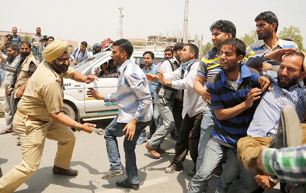 A policeman beats Kashmiri government employees during a protest in Srinagar.