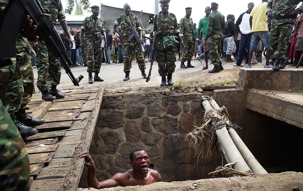 Jean Claude Niyonzima, a suspected member of the ruling party's Imbonerakure youth militia, pleads with soldiers to protect him from a mob of demonstrators after he emerged from hiding in a sewer in the Cibitoke district of Bujumbura, Burundi.