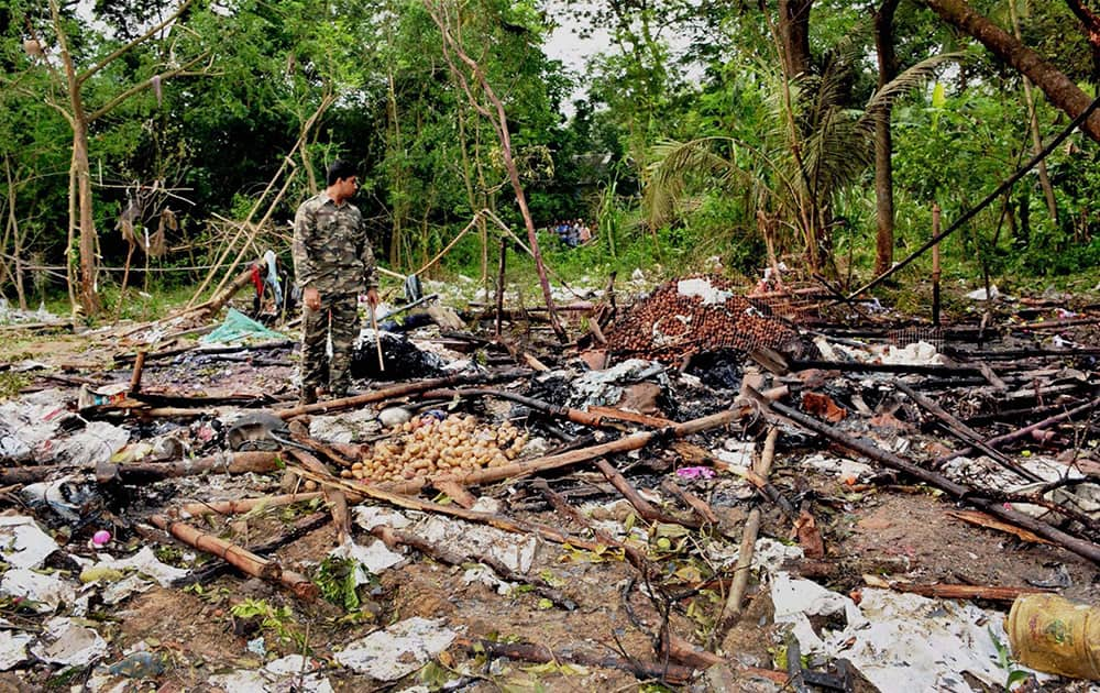 A Security officer investigates the site of a blaze at a firecracker factory in West Midnapore District, West Bengal. The blaze killed at least a dozen people, police said Thursday.