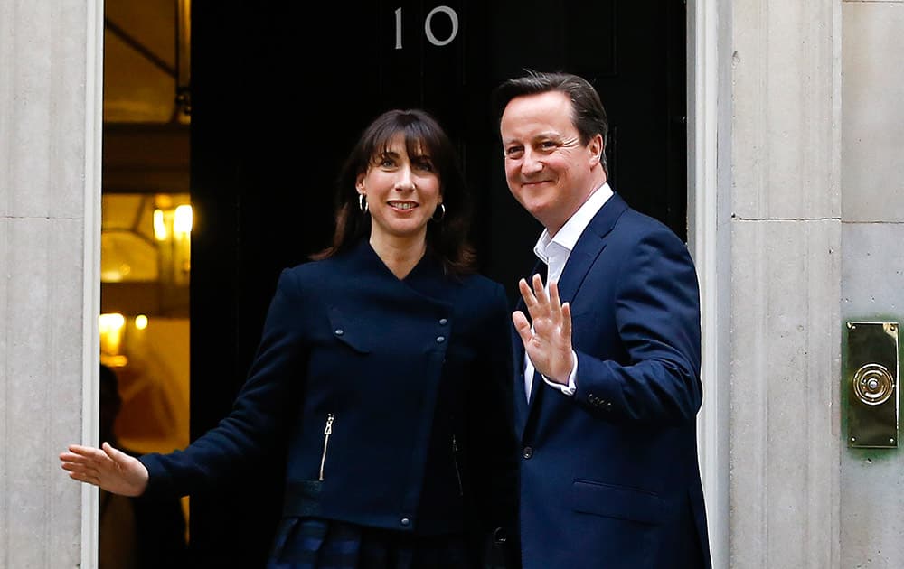 Britain's Prime Minister David Cameron and his wife Samantha return to 10 Downing Street in London. The Conservative Party surged to a surprisingly commanding lead in Britain's parliamentary election, with returns Friday backing an exit poll's prediction that Prime Minister David Cameron would remain in 10 Downing Street.