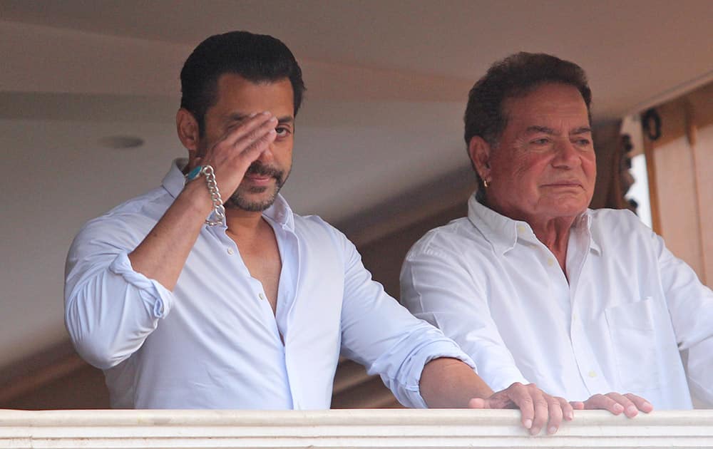 Salman Khan greets fans from the balcony of his home, with his father Salim Khan standing by his side in Mumbai.