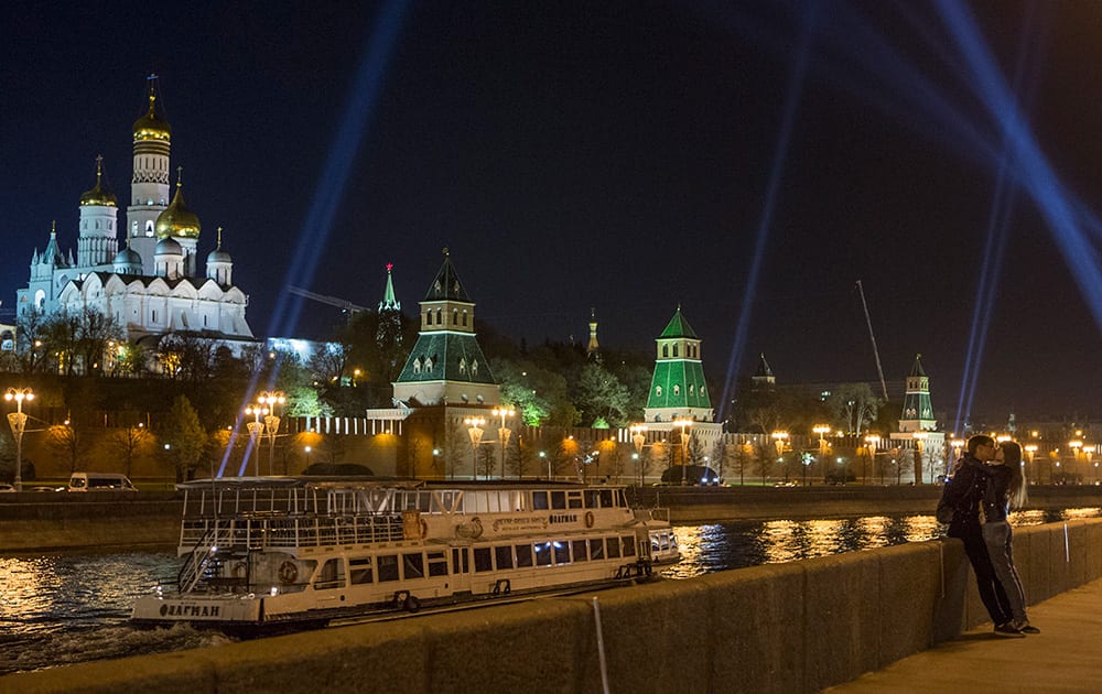 A young couple share a tender moment during a light show marking the 70th anniversary of the victory in WWII at the Kremlin in Moscow, Russia.