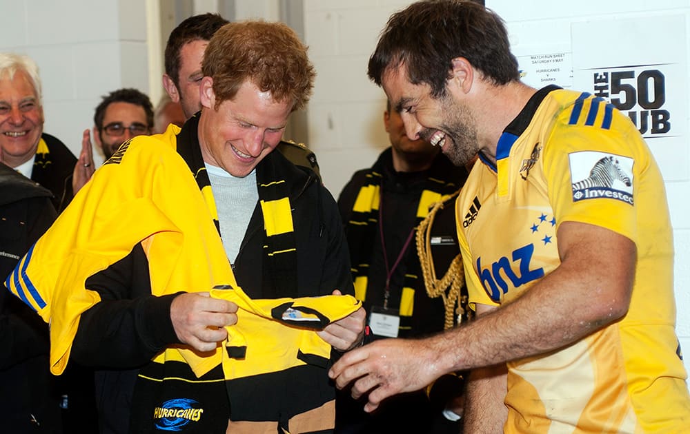 Hurricanes captain Conrad Smith presents Britain's Prince Harry with a personalized onesie for his brother Prince William's daughter, Princess Charlotte in the Hurricanes changing rooms after the Super Rugby against the Sharks at Westpac Stadium in Wellington, New Zealand.