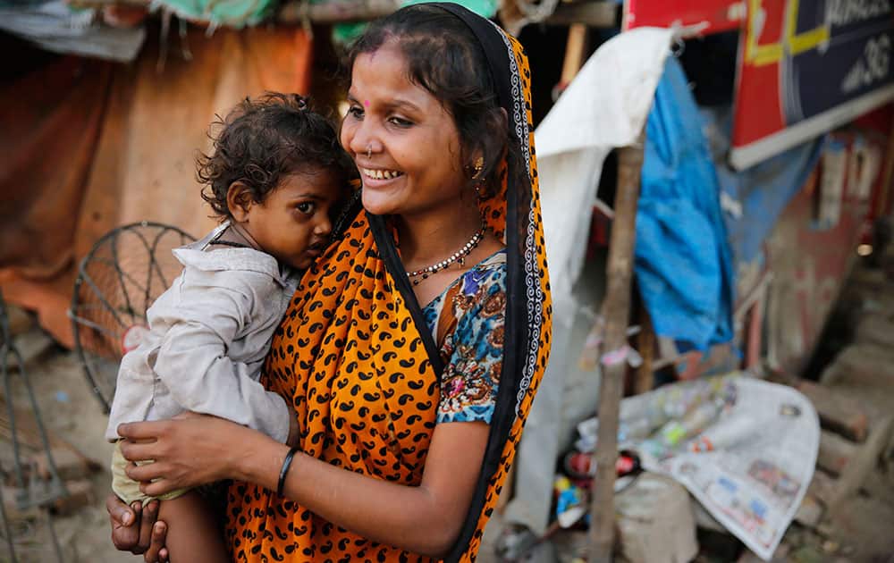 An Indian woman carries her child at an impoverished neighborhood on the eve of Mother's Day, in Allahabad.