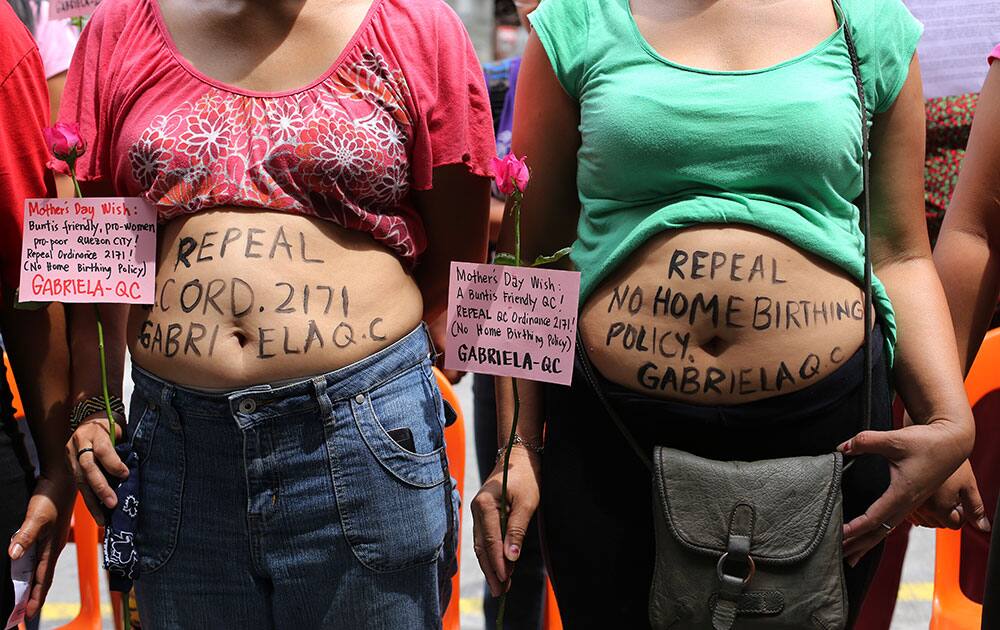 Filipino mothers show slogans written on their tummies as they join a protest calling for the repeal of a city ordinance prohibiting birth at home as they observe 