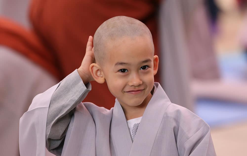 A boy whose Buddhist name is Chung A smiles as he touches his newly shaved head during a service to celebrate Buddha's upcoming birthday at Jogye Temple in Seoul, South Korea.