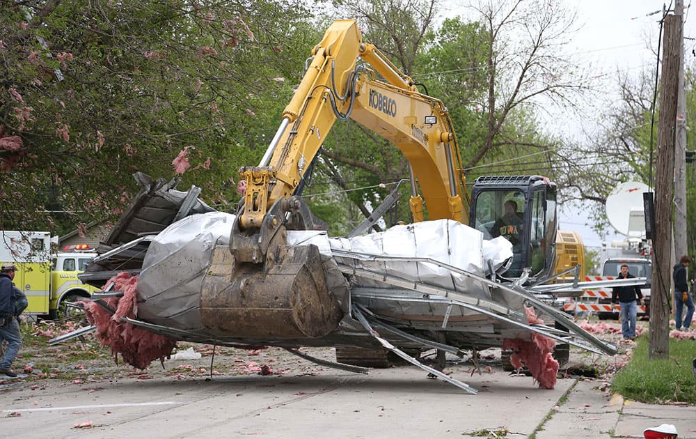 A portion of the South Central Calhoun High School roof, which was blown off by a tornado, is cleared from the street in Lake City, Iowa.